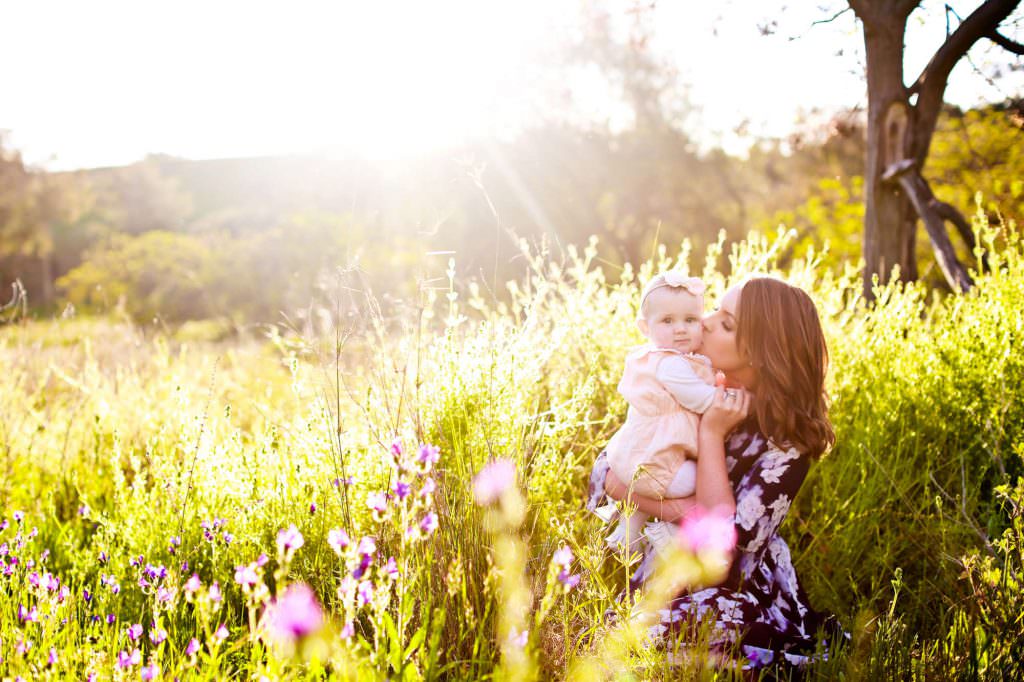 a mother kisses her baby on the hills of Tamworth with golden and green grass