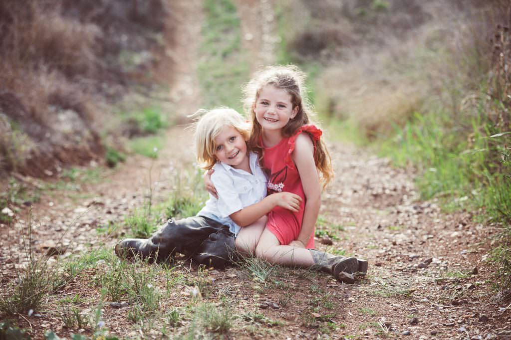siblings near Wallabadah NSW cuddle and laugh on a country road
