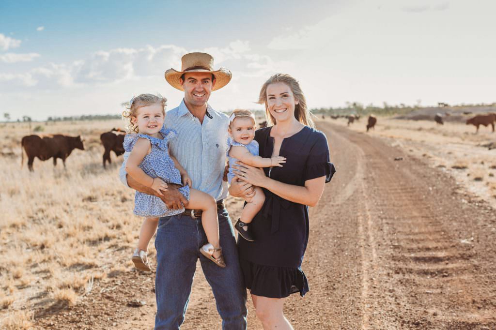 family in central Queensland on a dirt road with cattle in the background