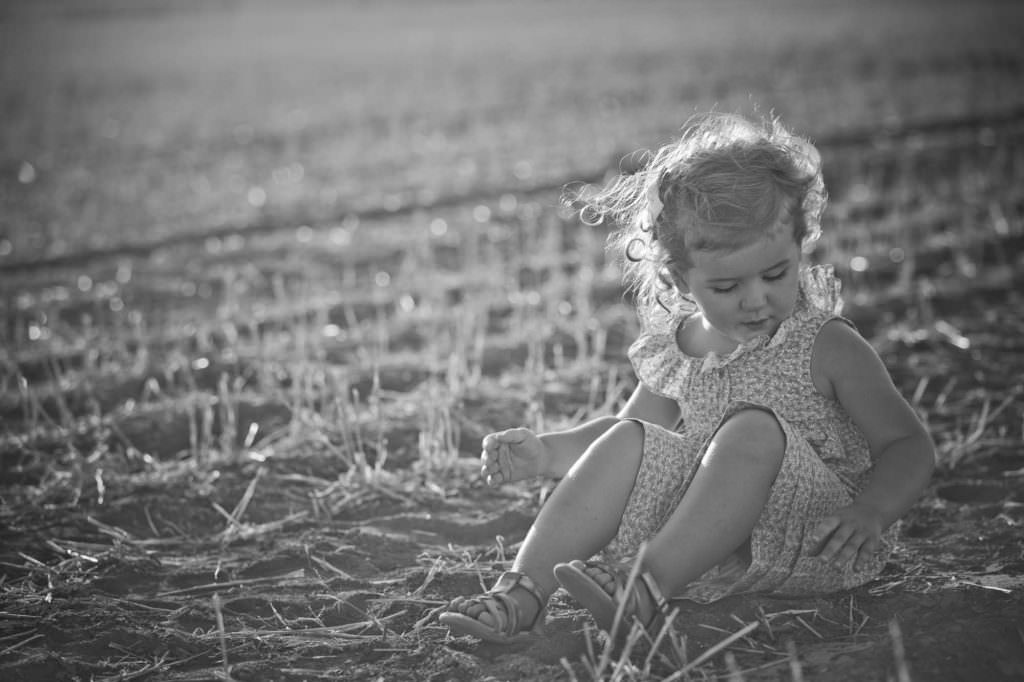 black and white photography shoot as a young girl plays in the paddock near outback QLD