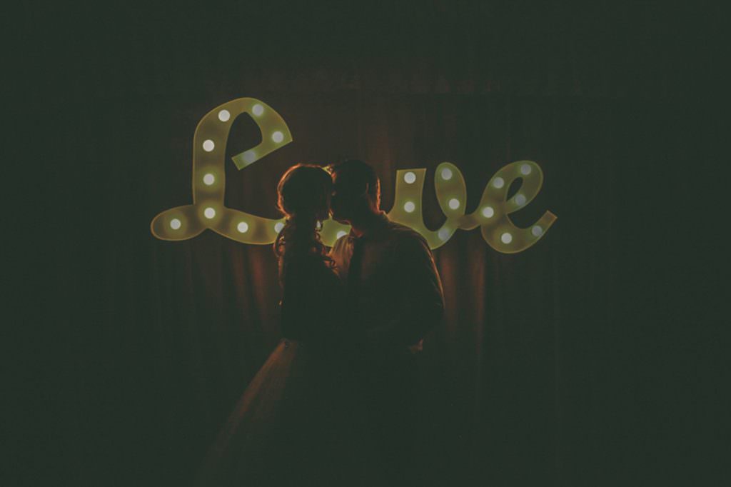 a couple kiss under the reflection of the lights of a love sign at Tangarratta vineyard Tamworth