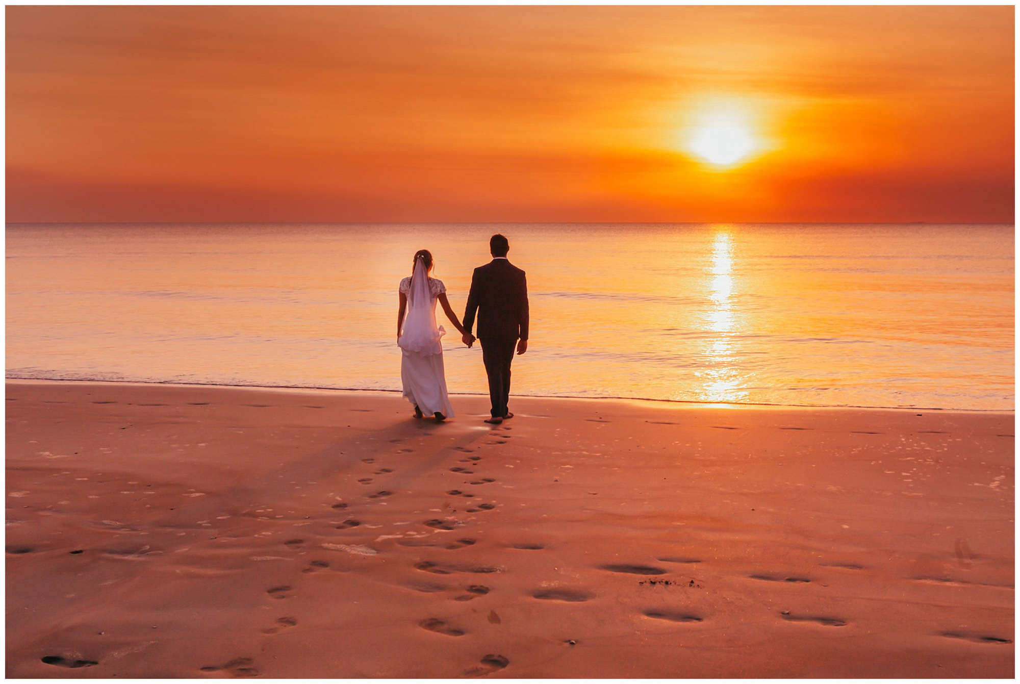 darwin sunset bright orange against a white wedding dress and grooms black suit