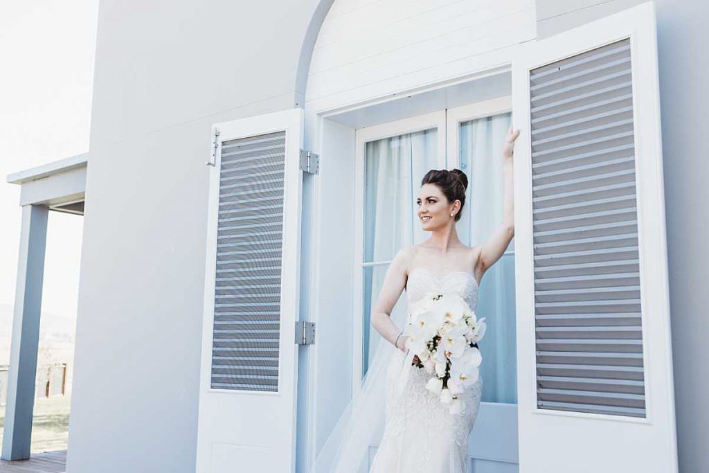 a bride in a vintage ground poses out the front of open doors at the homestaed of Goonoo Goonoo station