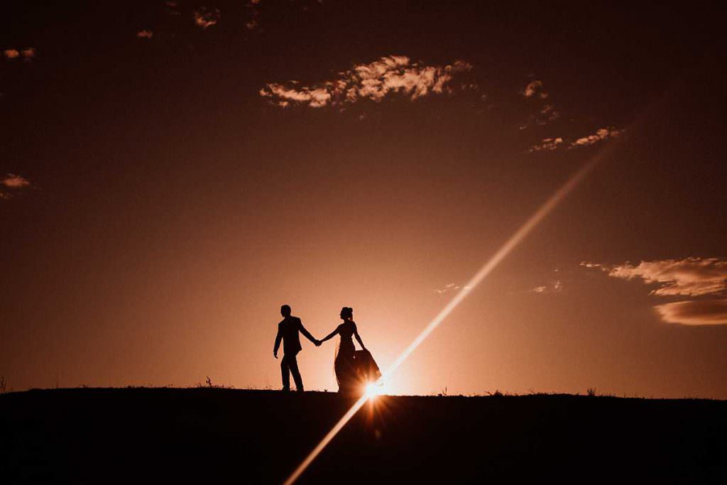 bride and groom walking on the hills of Goonoo Goonoo station as the sunsets
