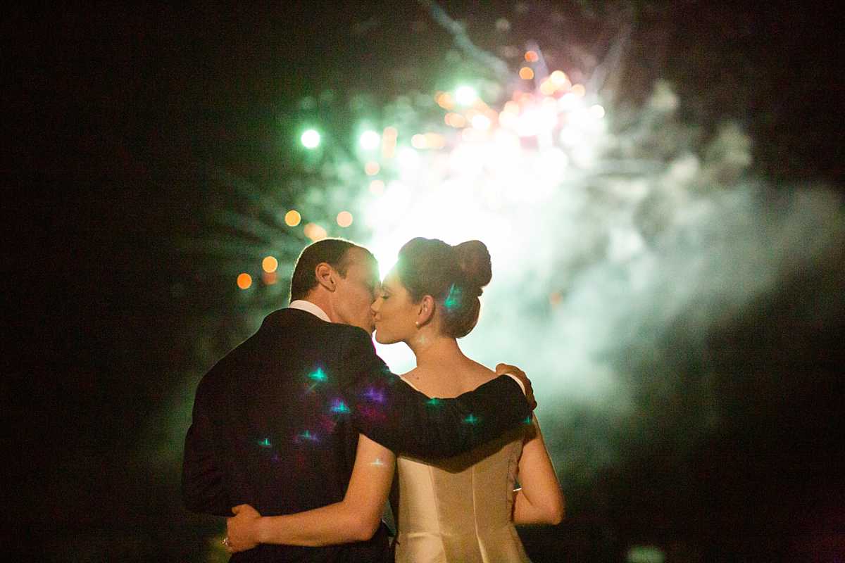 a couple kiss as fire works crack in front of them