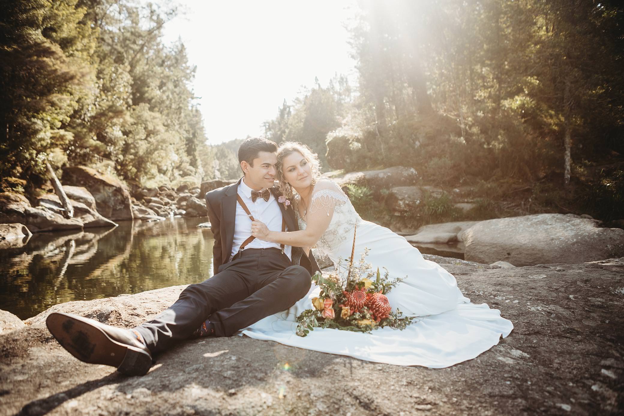 groom with brces on on poses on a rock with his bride at McClaren falls