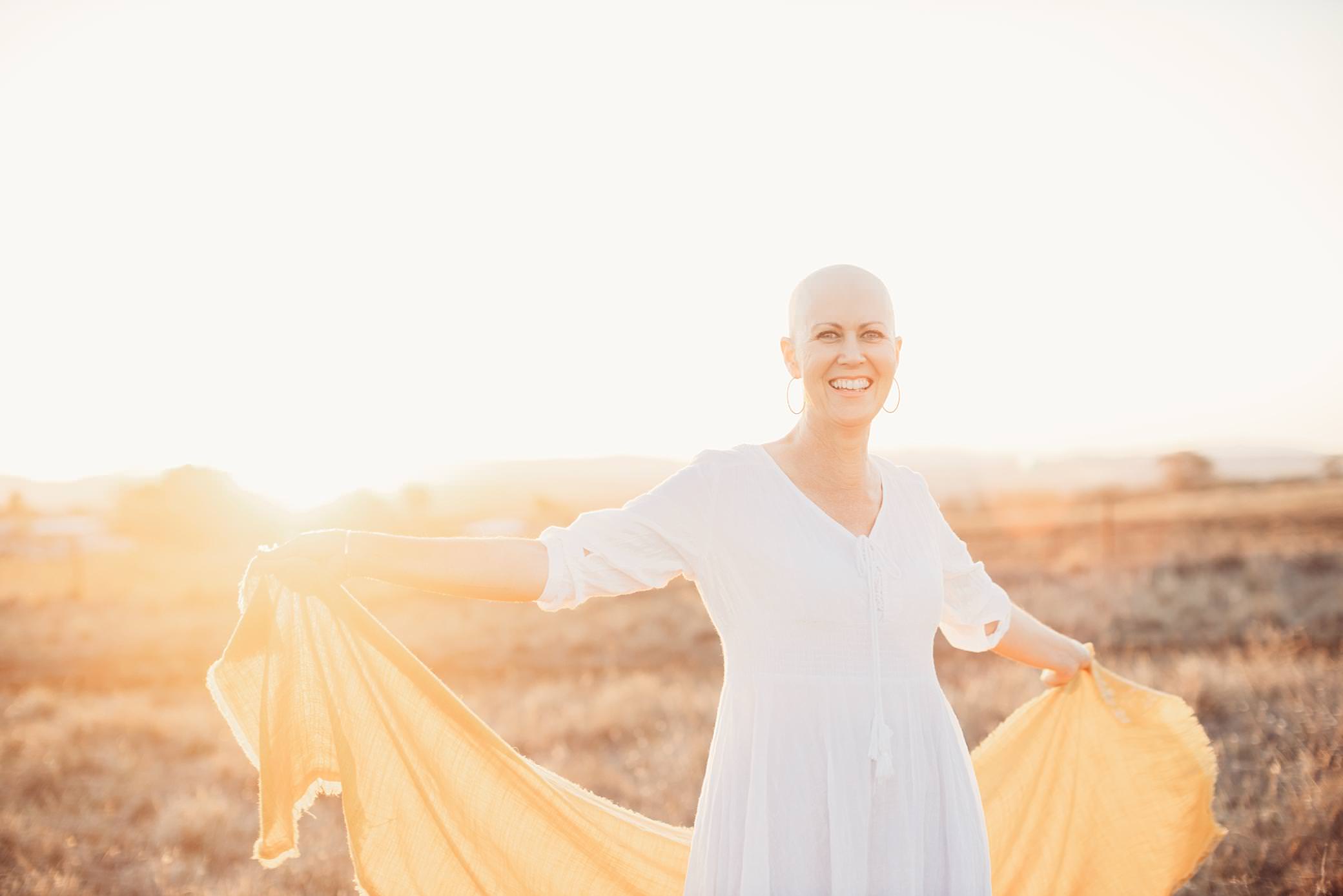 bald is beautiful for a woman in a white dress who has no hair due to chemotherapy.she also has a yellow scarf