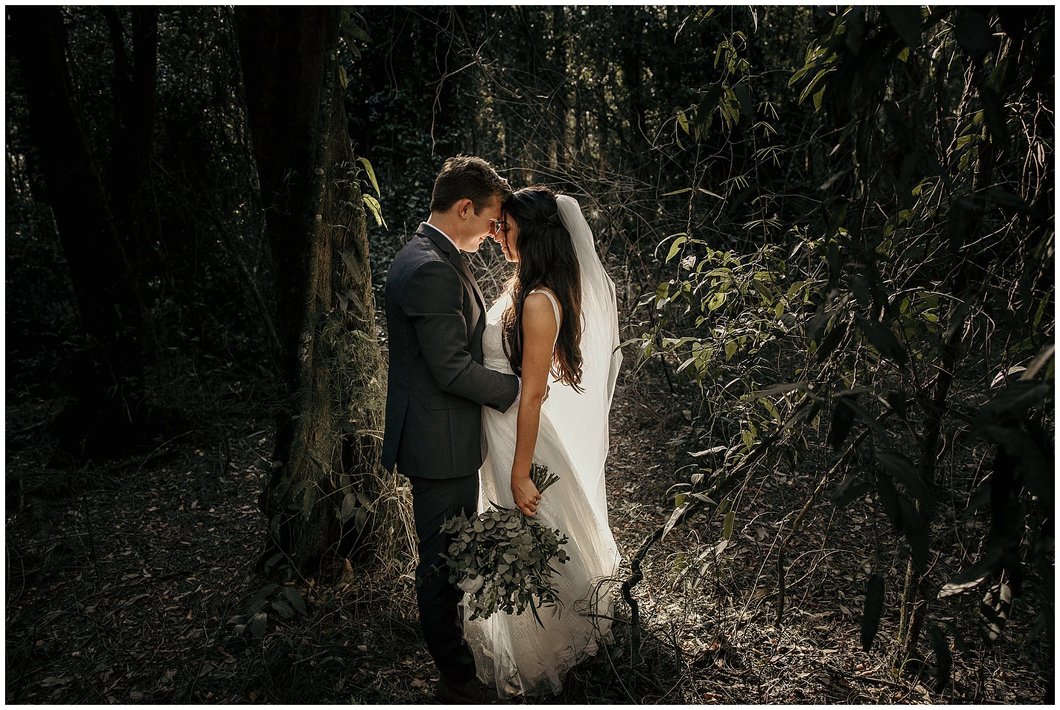 amongst fig trees a bride hold her bouquet as bride and groom breathe in sync near Forster for their wedding