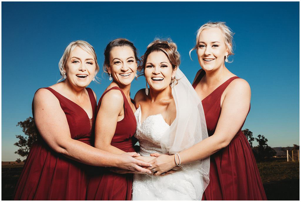 maroon bridesmaids and a bride in white and a big Tamworth blue sky as the girls laugh