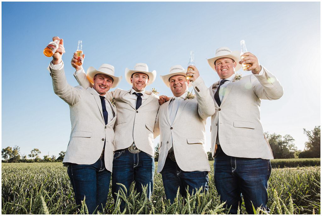 cheers with their beers as groomsmen in hats celebrate