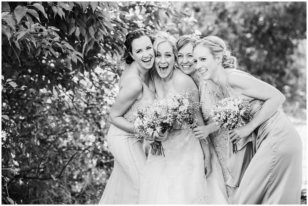 black and white of bride and bridesmaids hug together on a wedding day near Tamworth