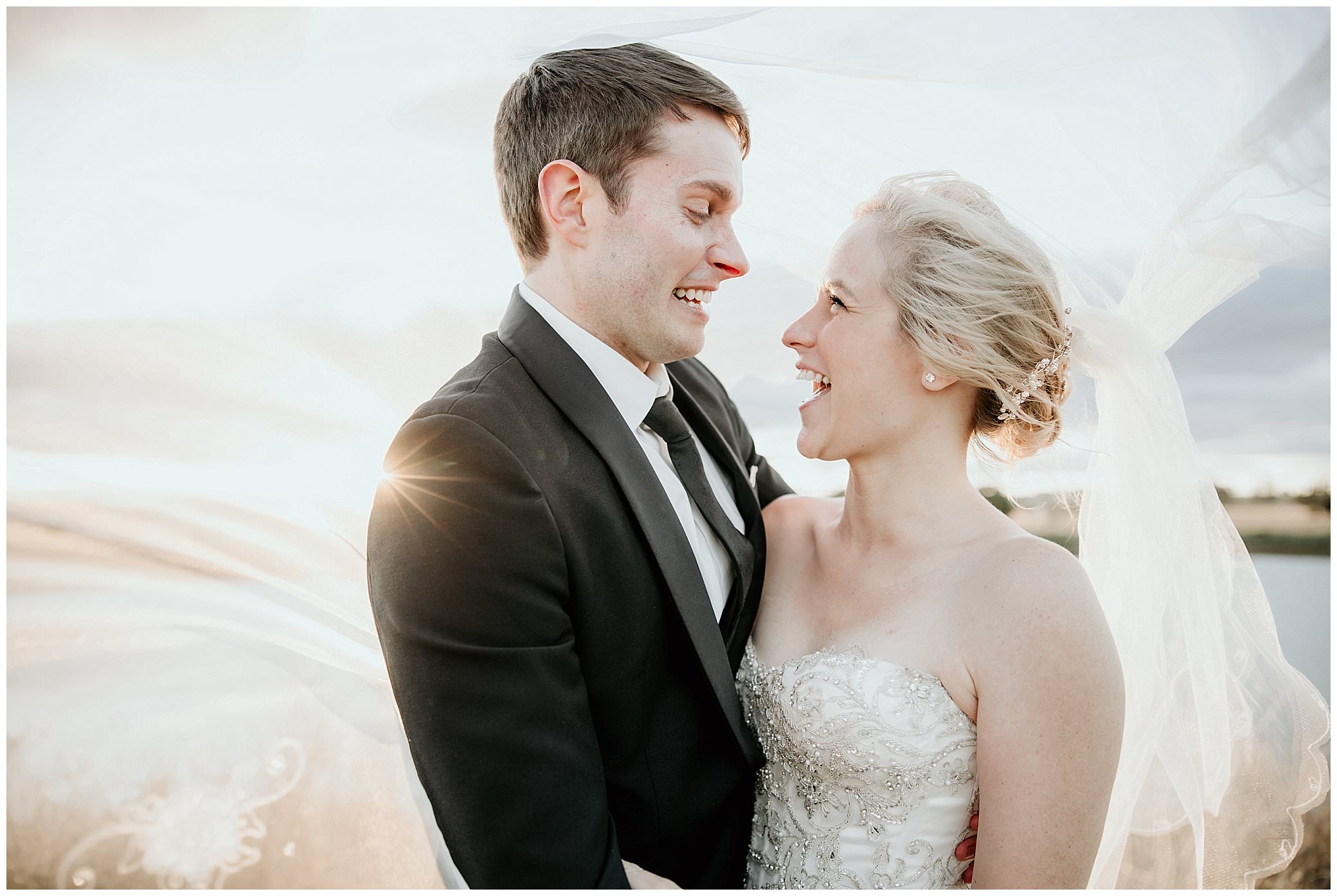 a look of surprise and laugh as a bride and groom play under the brides veil as the sun peers over the groom shoulder as Tamworth NSW wedding photographer captures this moment