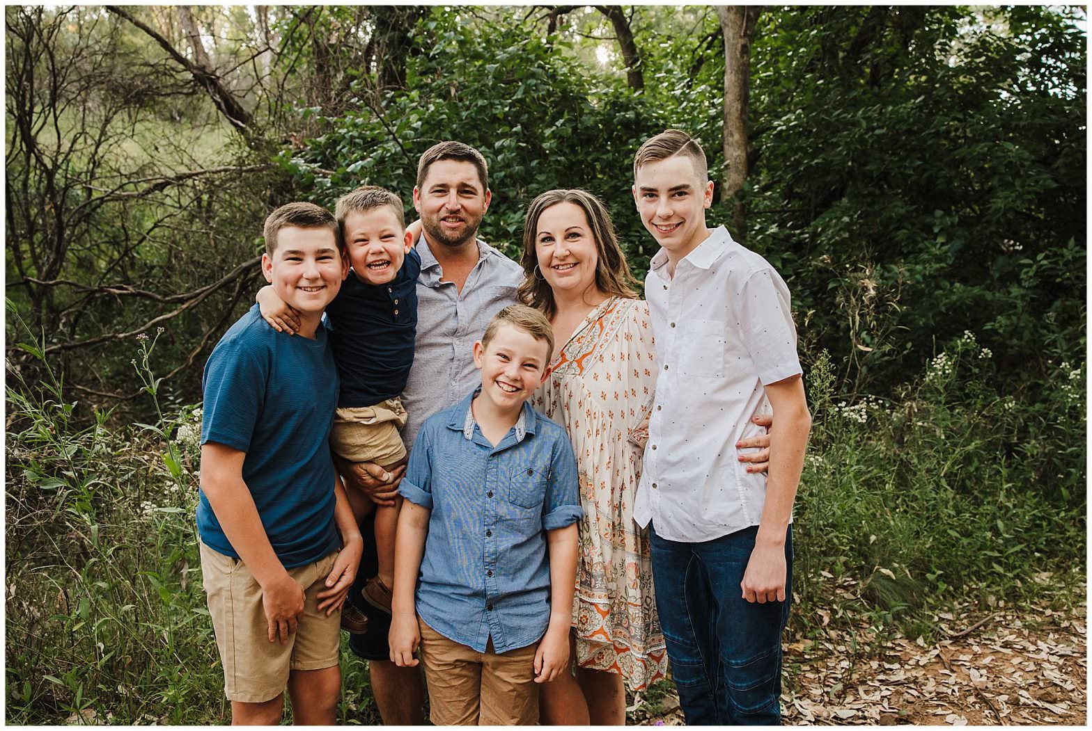 family of four from gunnedah hug close for their family shoot in a forest