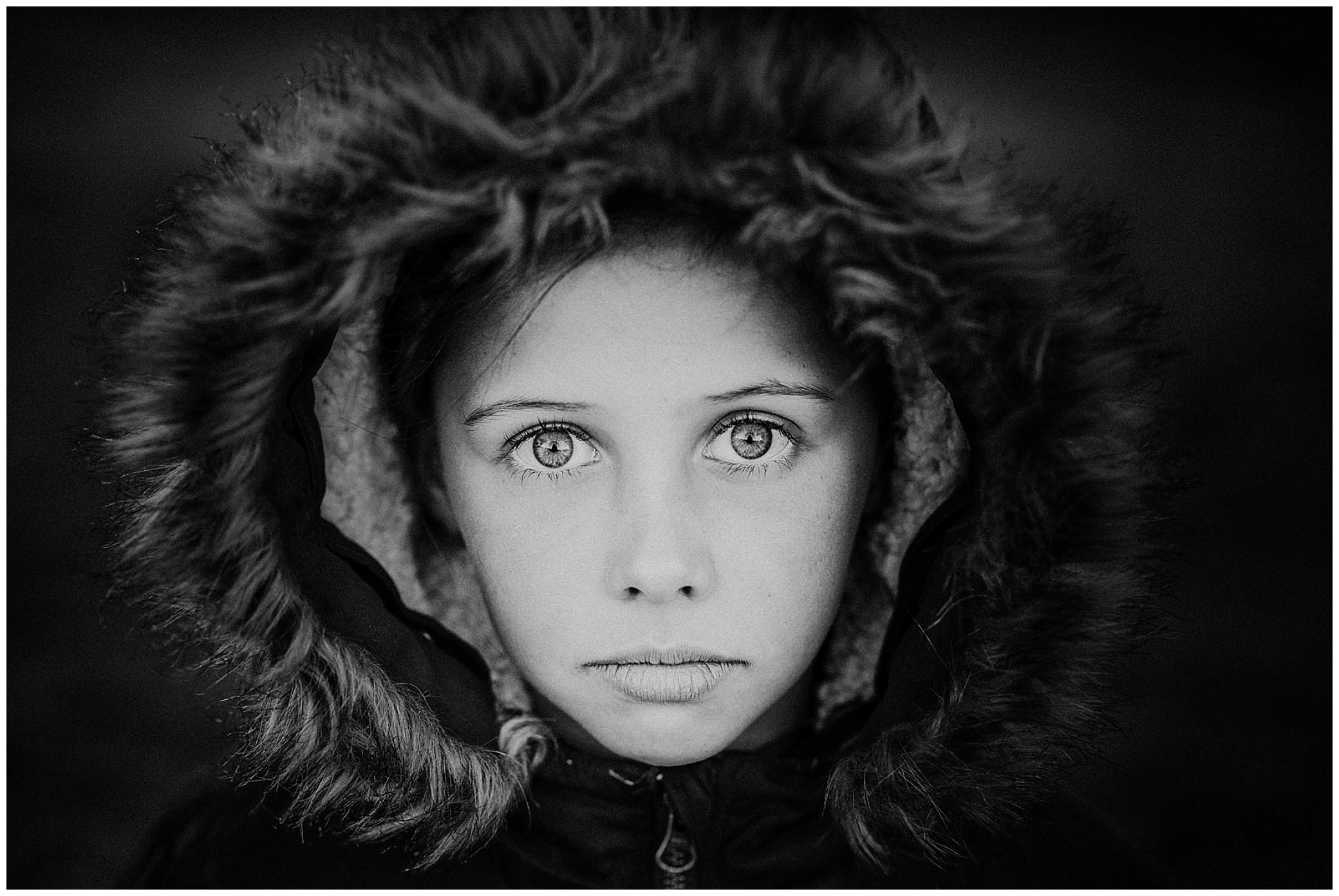 black and white photo a young girl with a wool coat around her head and piercing eyes look at Tamworths best family photographer Karissa
