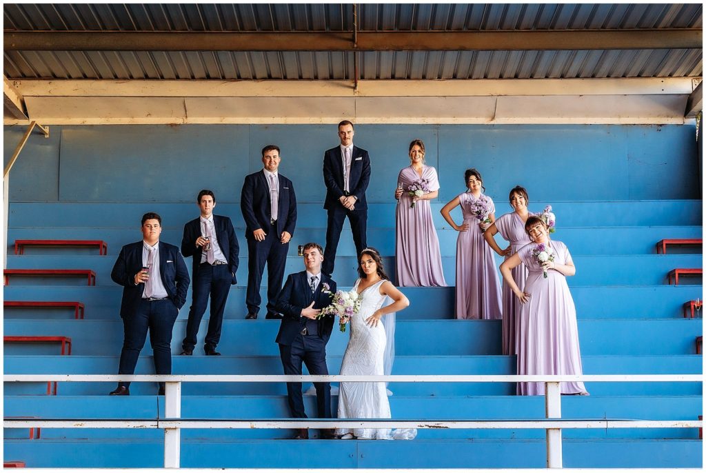 bridal party pose on baby blue tiered seating holding flowers from posies florist Tamworth