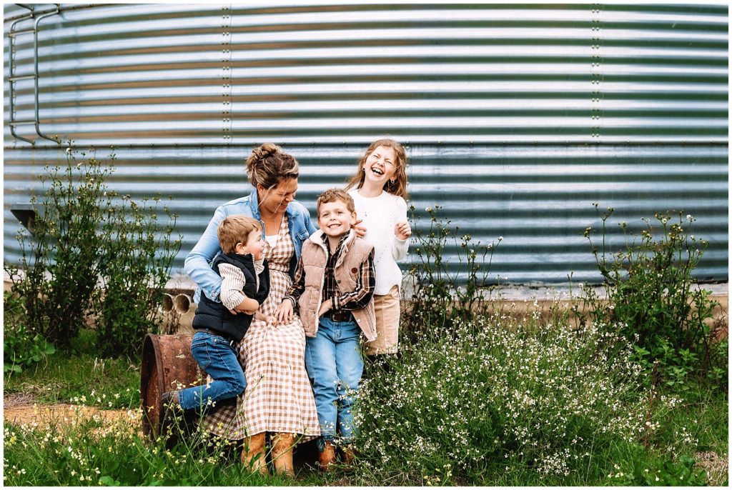 laugh with a mum and her 4 children with a silo as a background and wild flowers