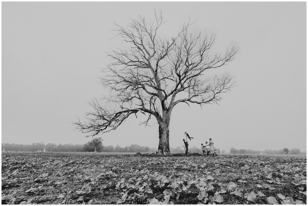black and white photo of a family of five with a huge dead tree