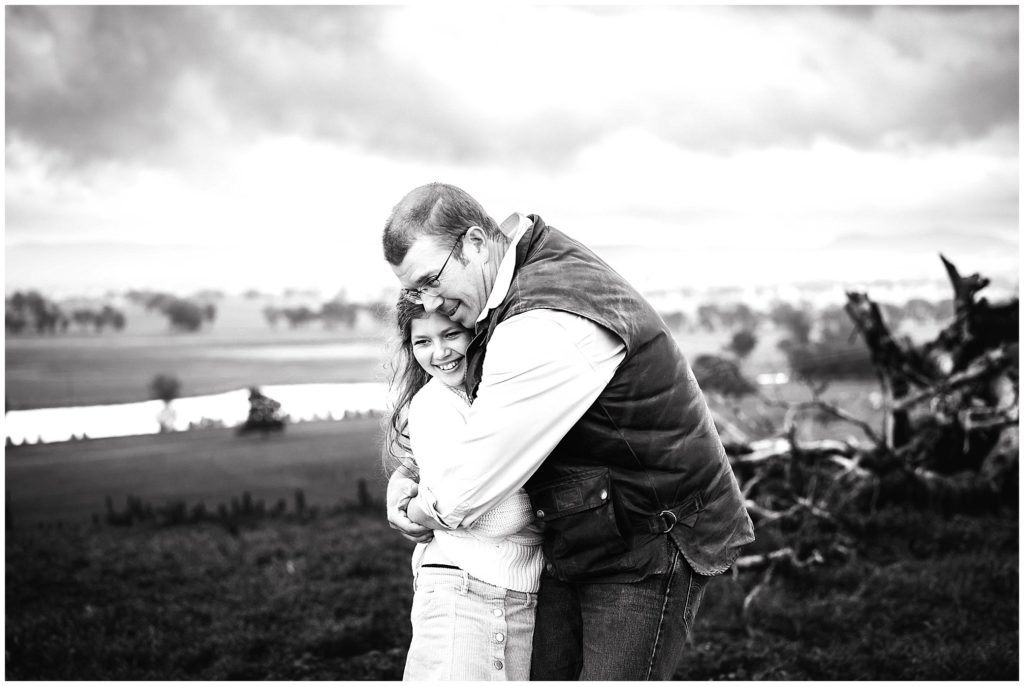 A dad cuddles his daughter balck and white photo on the top of a hill near Cowra NSW