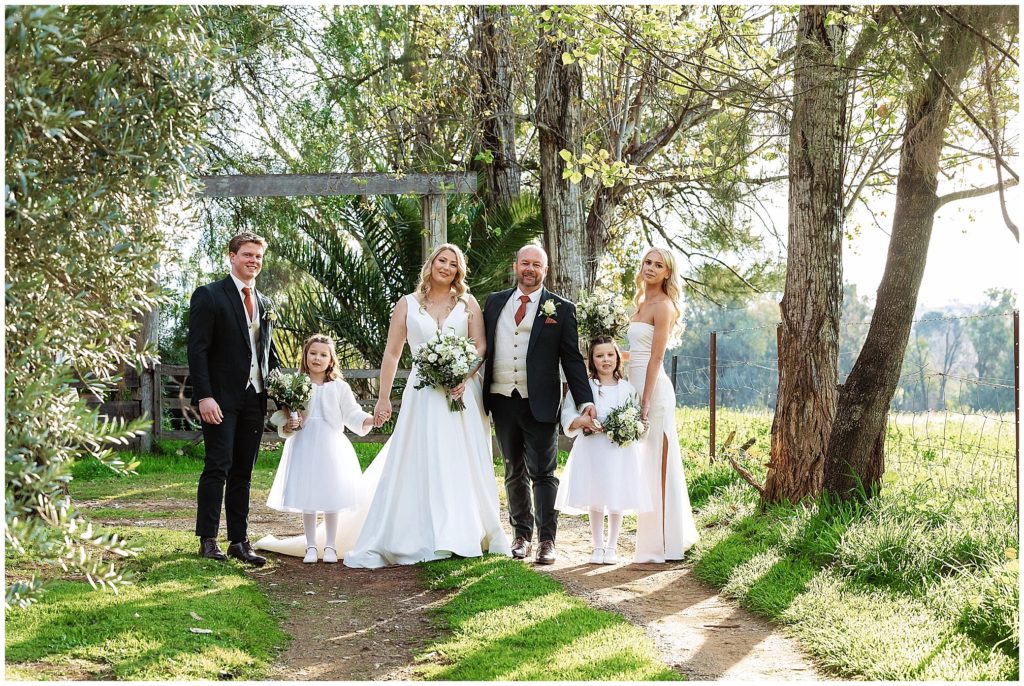 a bride a groom and their children in the bridal party walk on a road near the pavillion function centre tamworth nsw