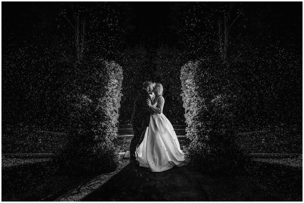 champagne spray for a bride and groom at their reception in the gardens at the Pavillion function centre Tamworth. off camera lights captures the water drops perfectly as they kiss