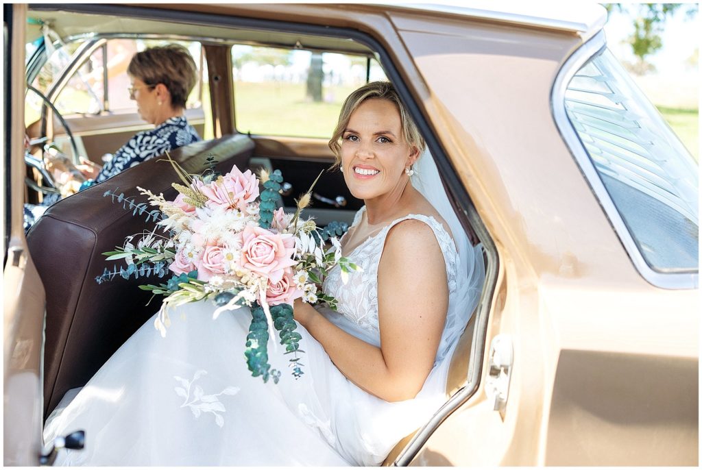 a bride in a vintage car arrives at her wedding