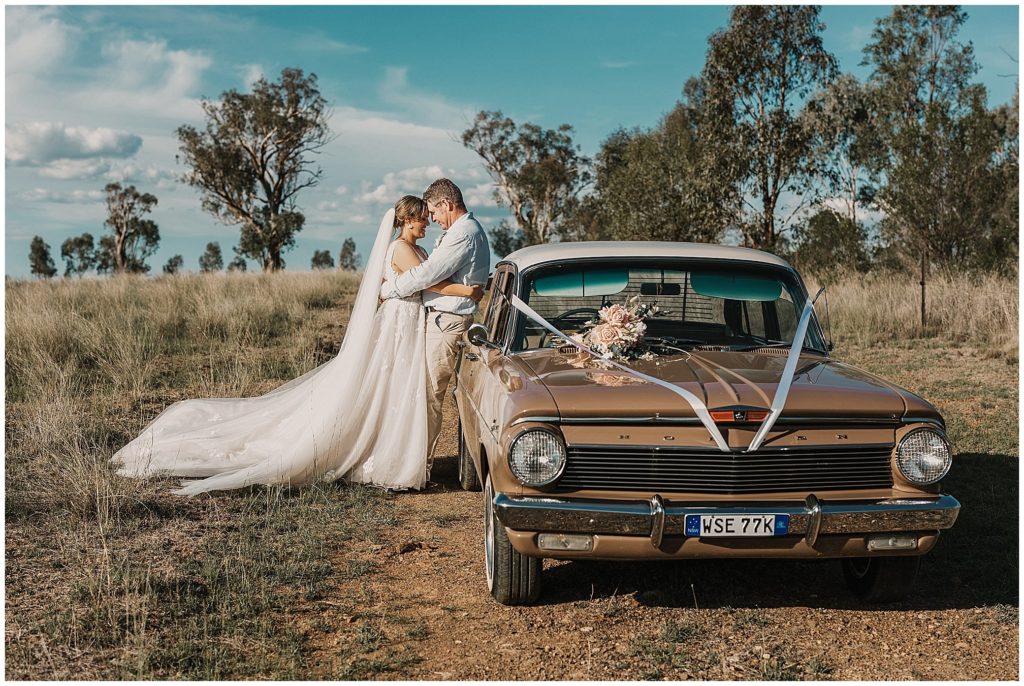 vintage car and a bride & groom as they cuddles