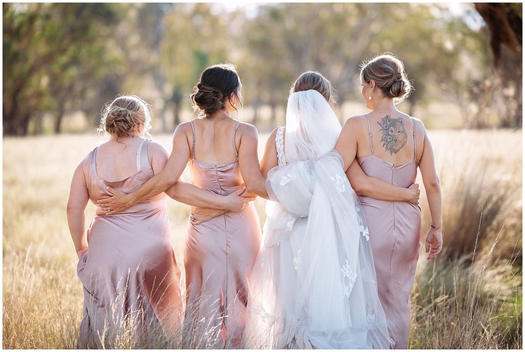 a bride & her bridemaids in pink dresses sun is setting tamworth in the long grass at Dathem park woolshed