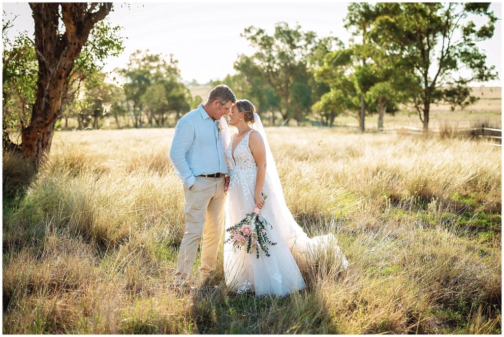wedding photos in the long grass at Dathem park woolshed as a couple chat