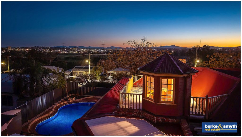 overlooking Tamworth city as the sun goes down Image photography captures a rooftop and a pool at night for a house that is for sale