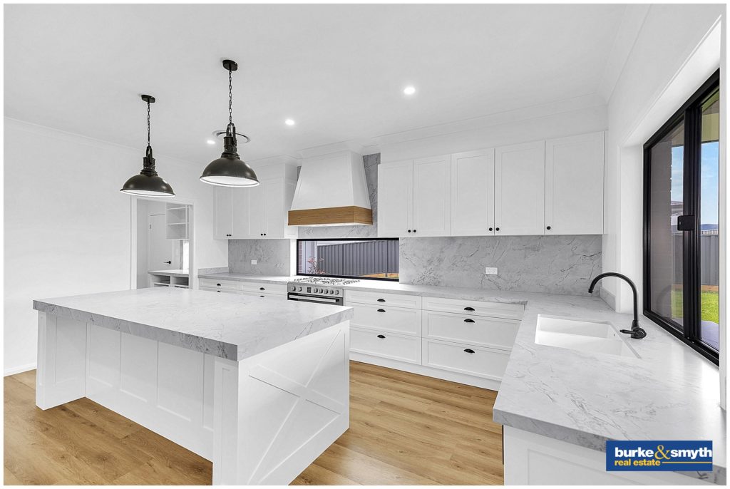 a white kitchen with stone benchtops is photographed by local real estate photographer Karissa Tuckwell