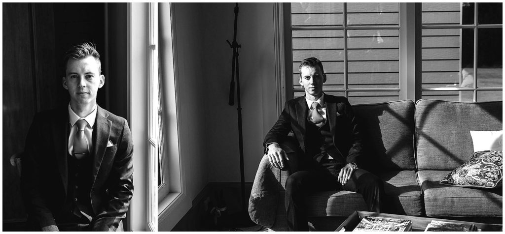 black and white of a groom asthe sun comes into a window