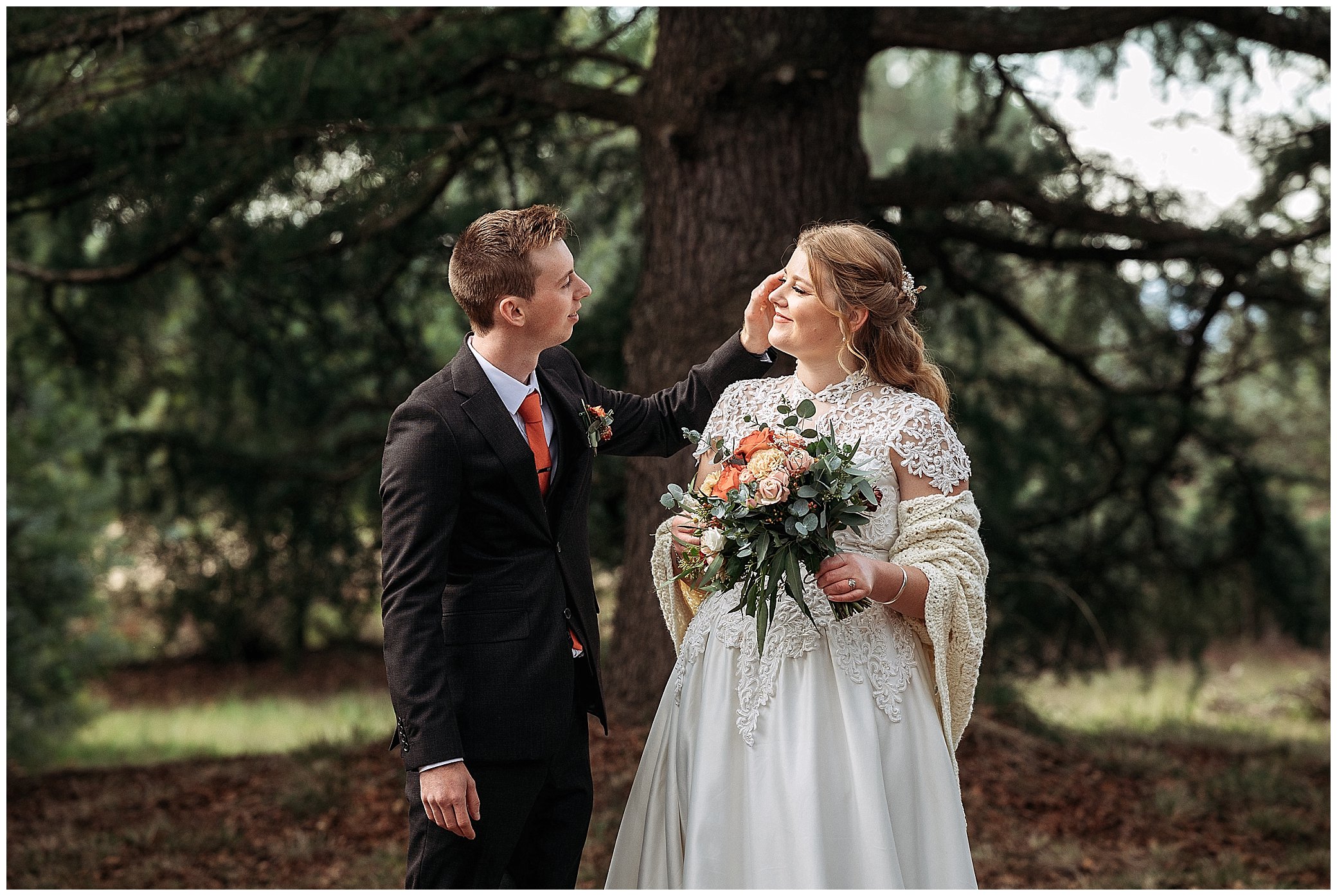 a bouquet made by Rosemerin florists is held by a bride with a shawl as her hsuband brusher her cheek with his hand near Uralla NSW