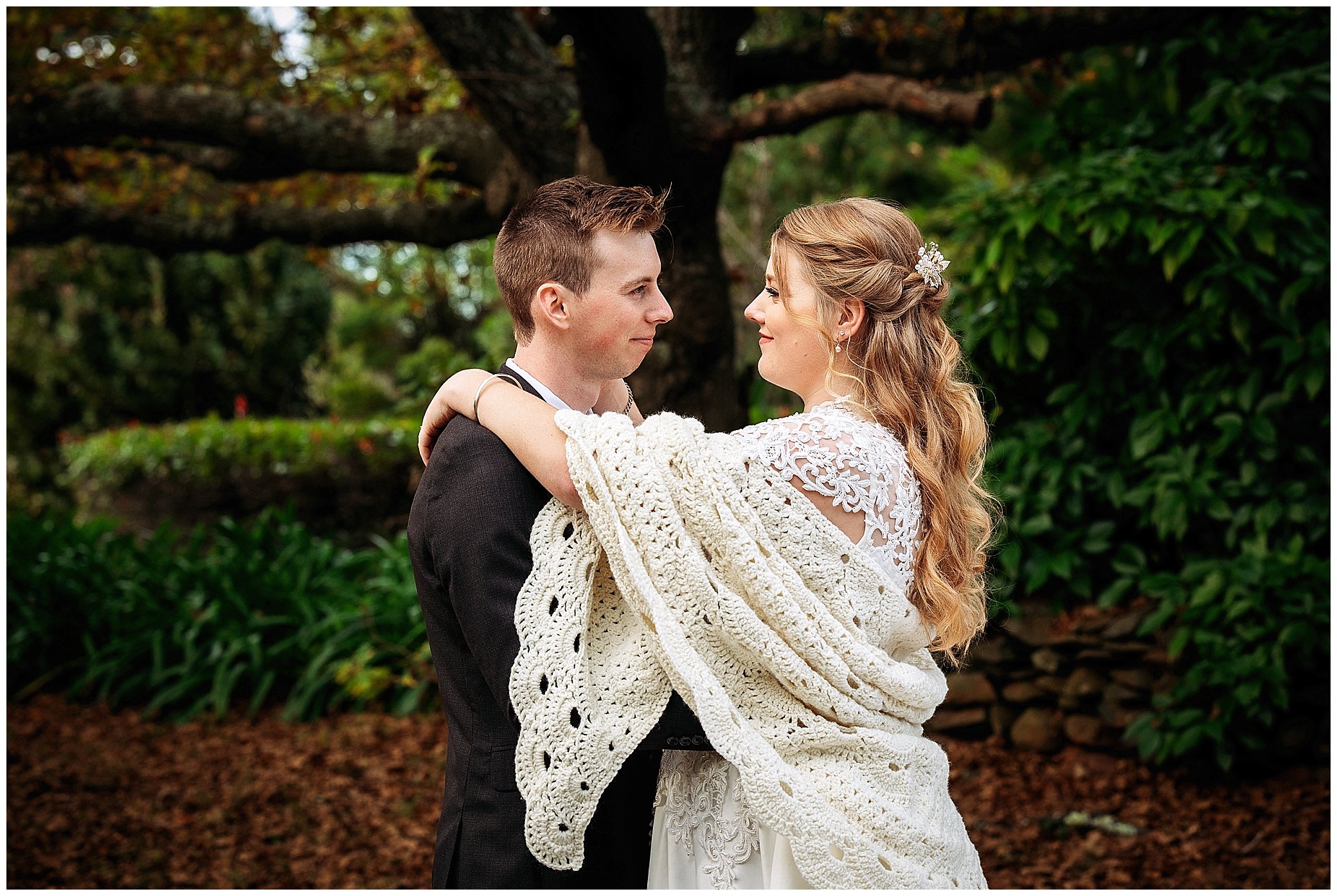 a shawl and a cuddle under a big oak tree at rock abbey gardens Uralla for a bride and groom