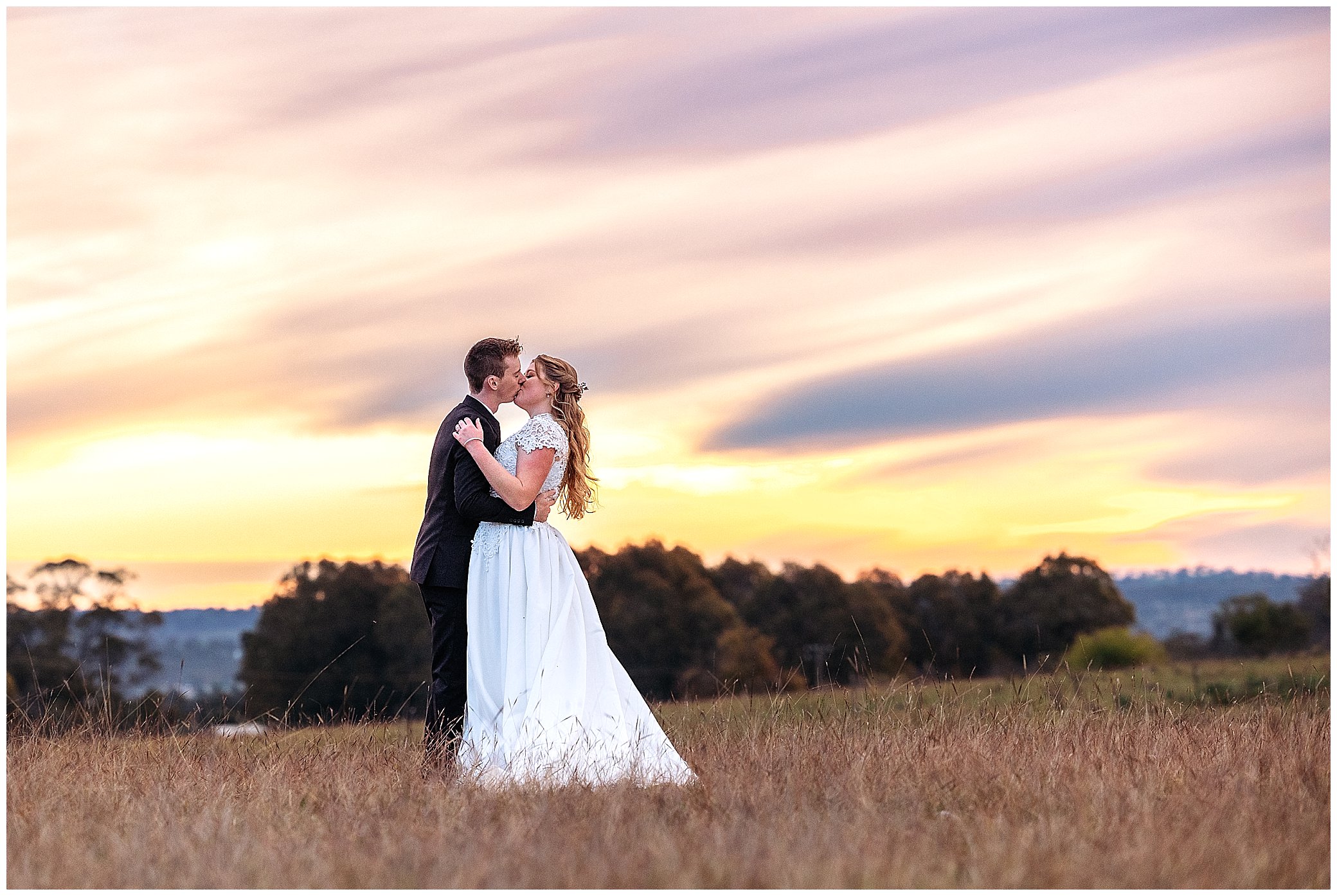 a bride and groom kiss as the sunsets behind them on a wedding day at Rock Abbey Gardens Armidale