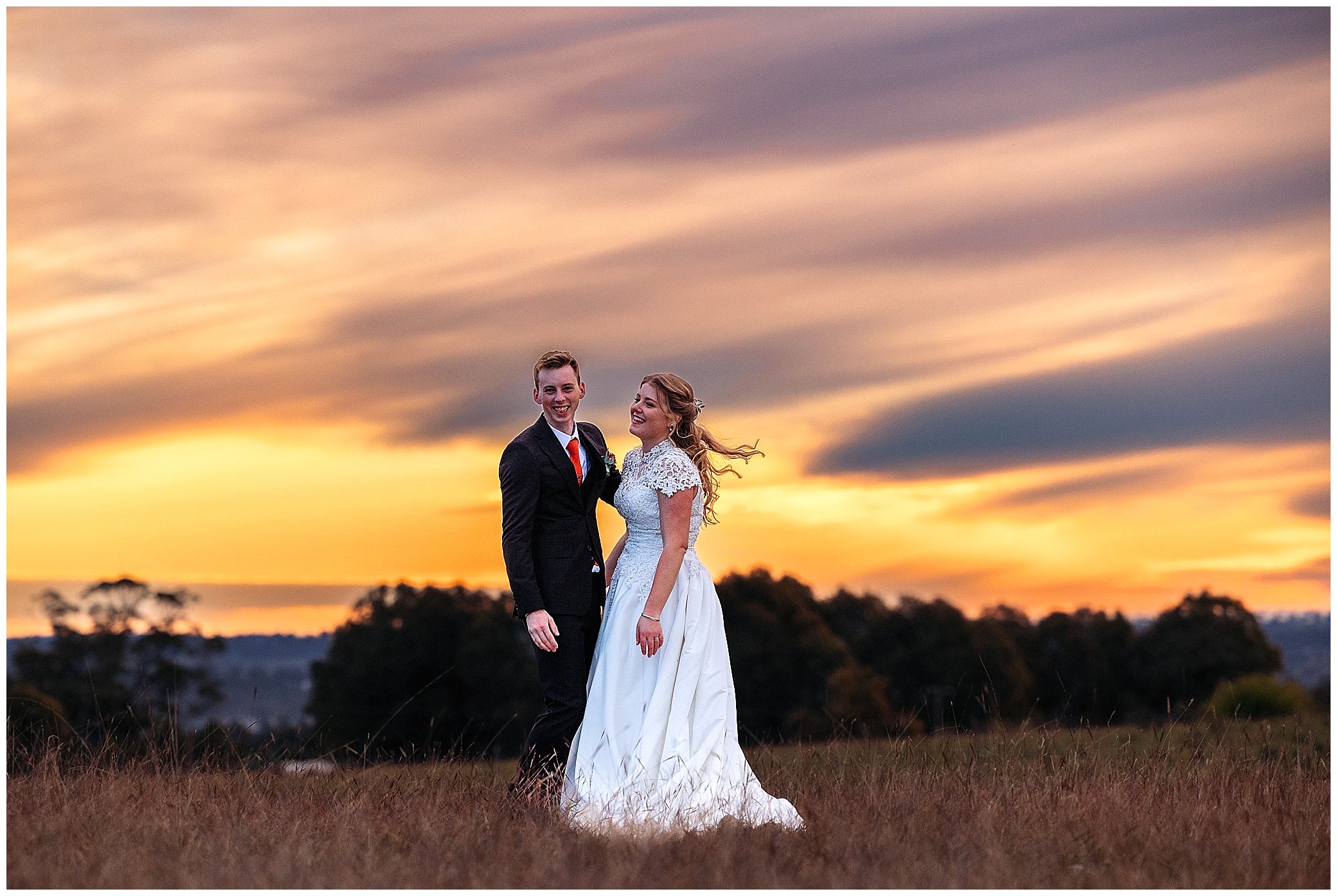 a bride and groom laugh as they hold each other as the sunsets behind them on a wedding day at Rock