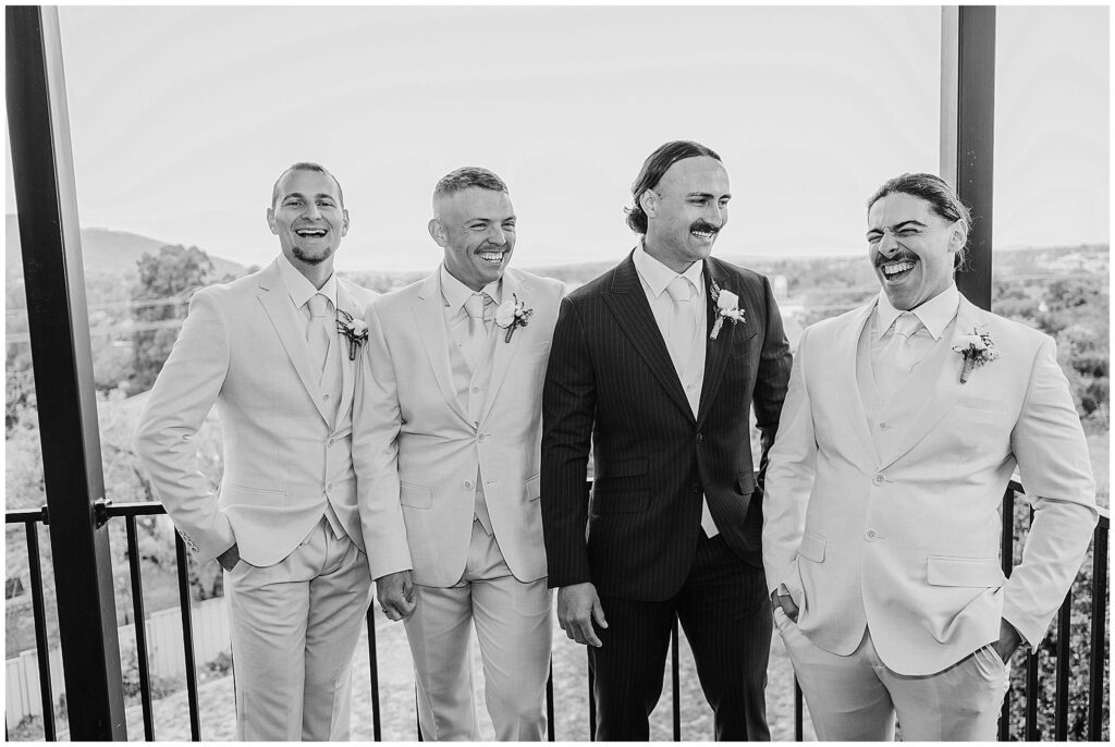 black and white photo grooms laughing on a balcony in Tamworth NSW