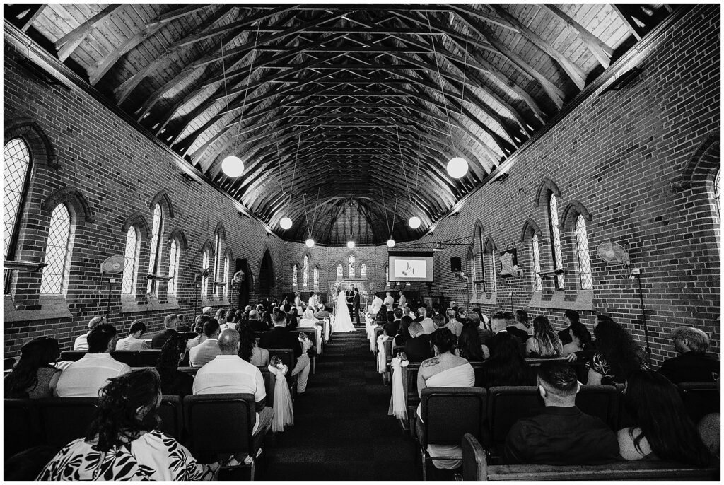 Black and white photo of a wedding Manilla NSW inside the church as a couple make their vows to each other