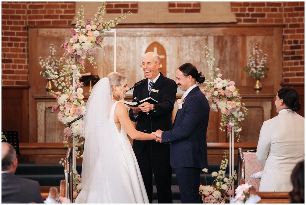 a minister laughs in the church at Manilla NSW as a couple say their vowels