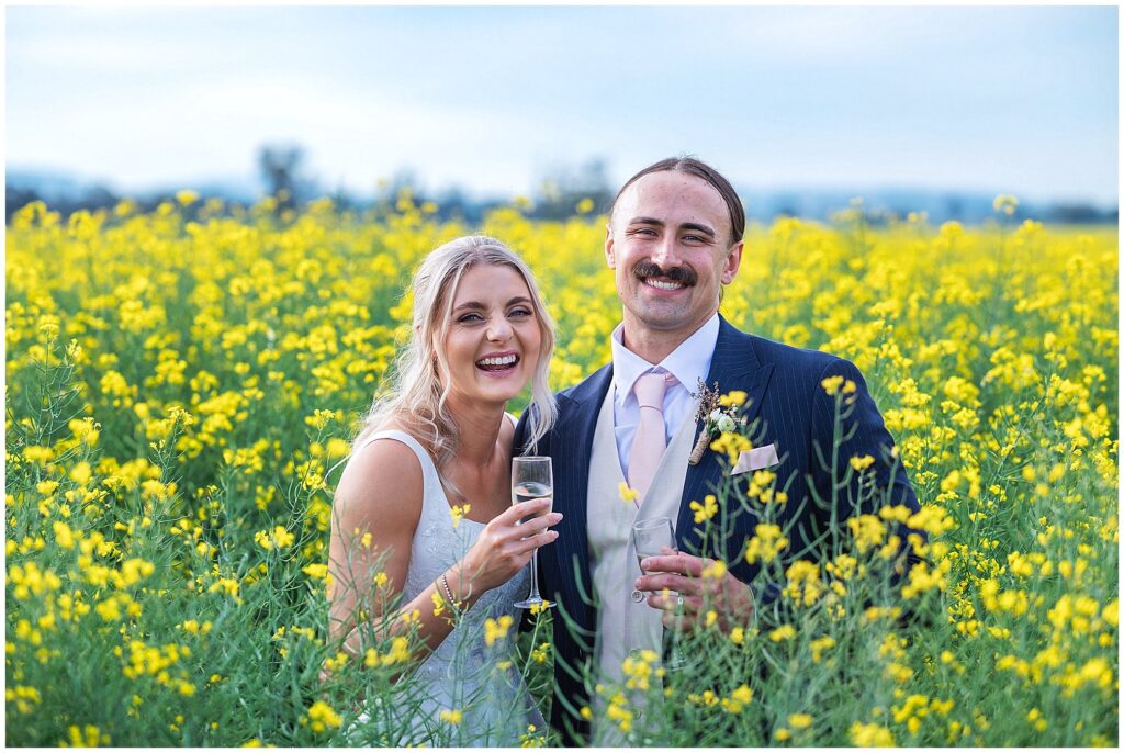 in a yellow canola crop a couple enjoy a glass of wine