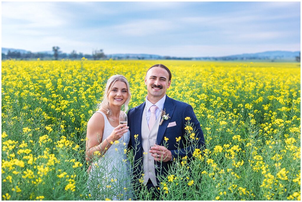 a canola crop of yellow and a bride and her groom smile