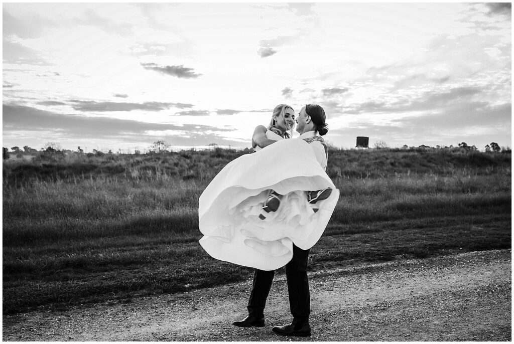 Black and white photo of a spin shot as a groom hold his bride